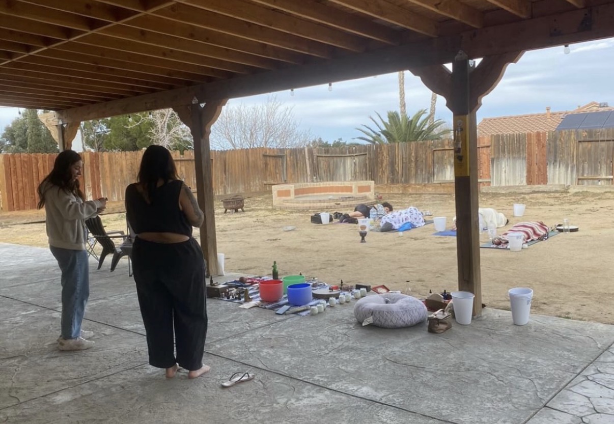 Participants laying on the dirt yard beside Kambo buckets and singing bowls during a Mayan fire ceremony collaboration