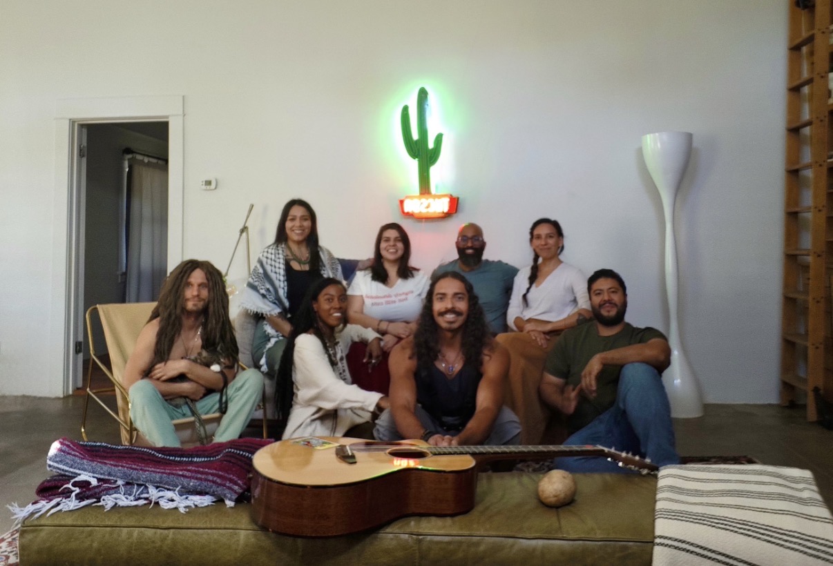 Group gathered on couches beneath a glowing neon cactus sign