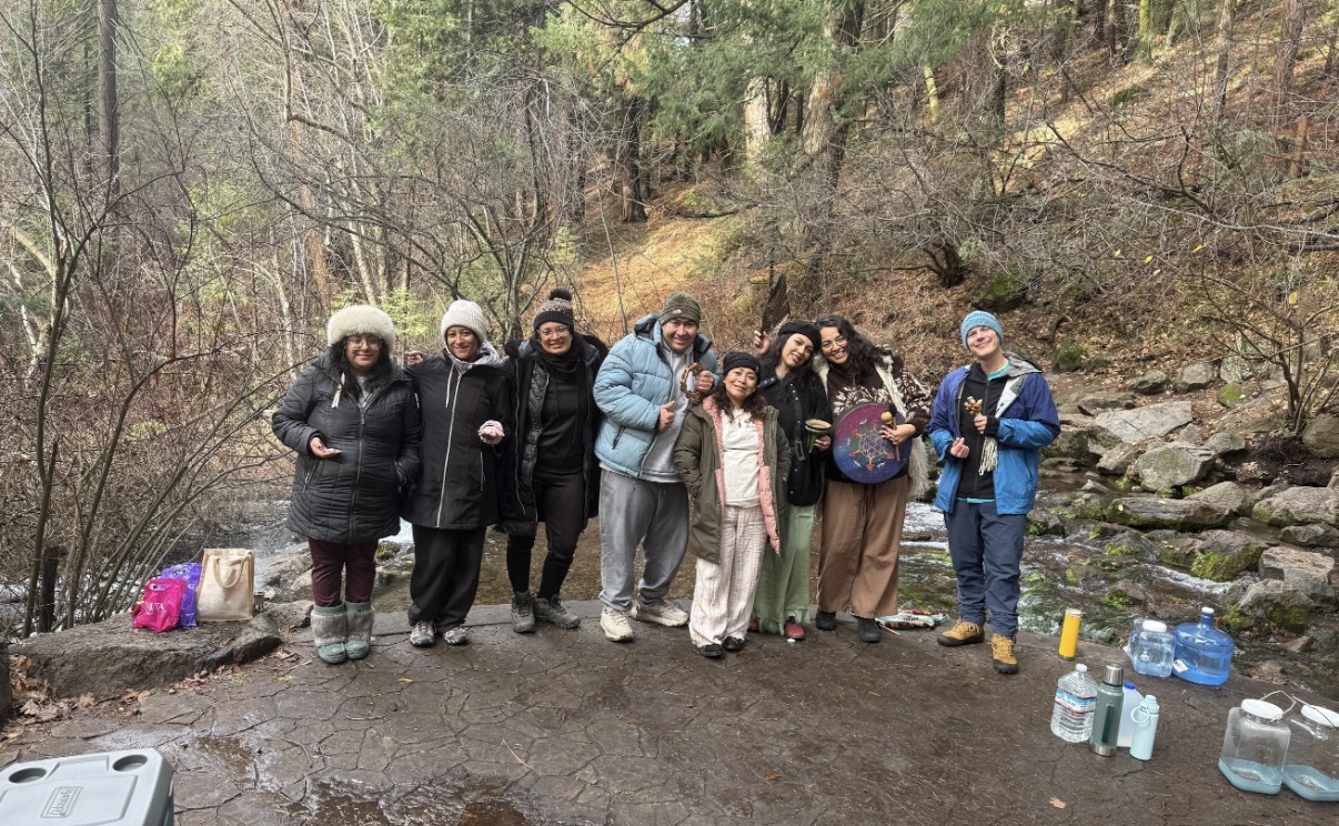 Group standing together beside a mountain creek in winter