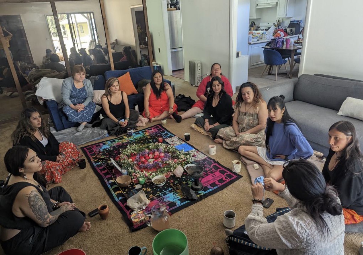 Women seated around a flower altar in a home womb healing ceremony