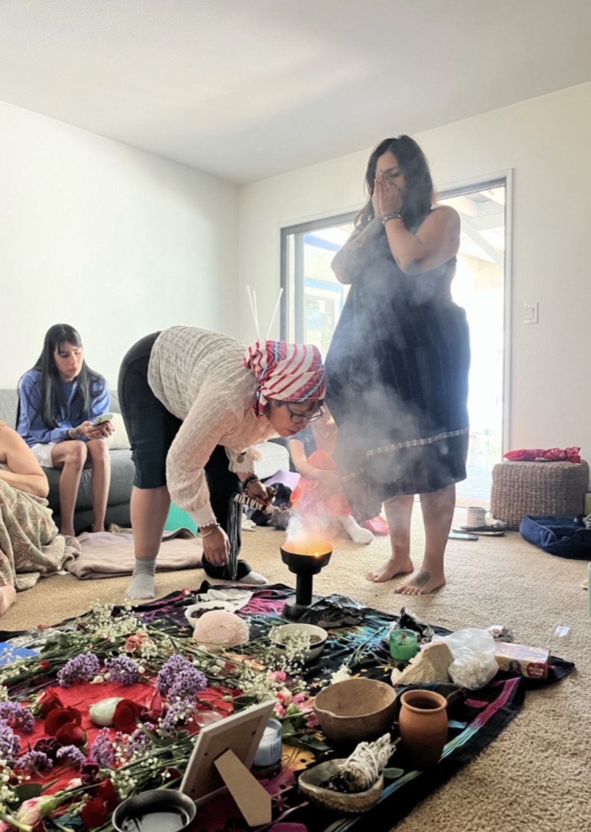 Copal smoke rising over Ryanne as she receives a healing beside a flower altar