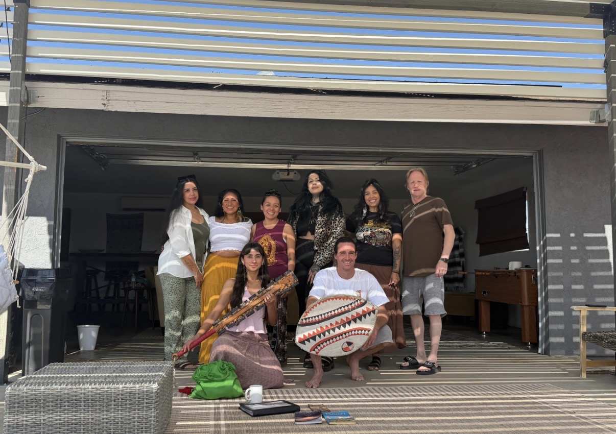 Group gathered beneath a pergola with drums and rattles