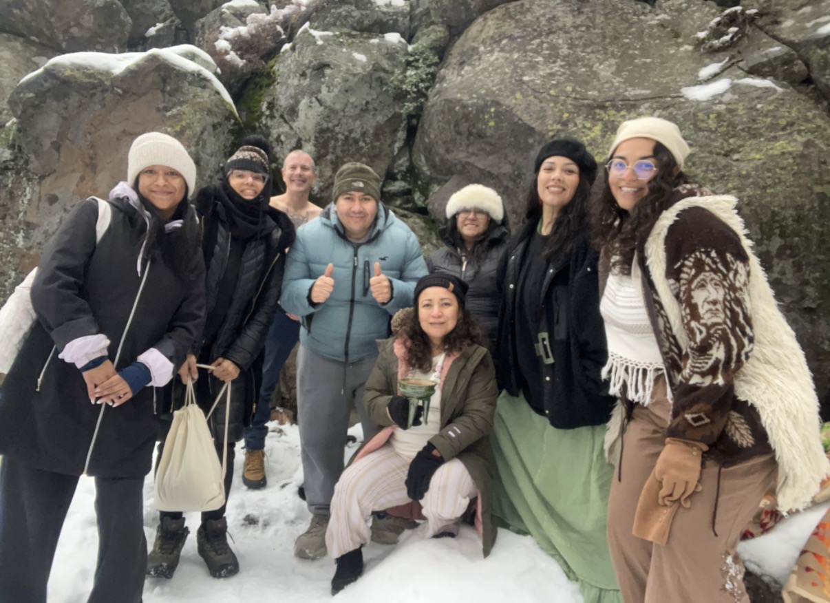 Group gathered in the snow among great stones, one holding a ceremonial cup